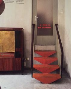 a red stair case sitting next to a wooden cabinet