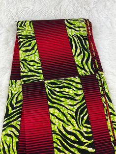 a close up of a red and green tie on a white rug with black stripes