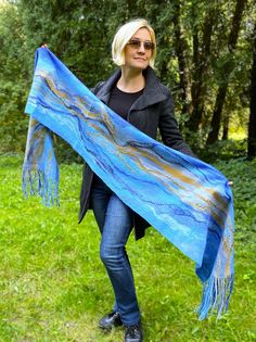 Stylish long handmade felting on silk scarf made of delicate Australian merino wool in sky-blue and blue colors with a touch of golden honey color. The product on one side with an abstract pattern, decorated with silk, lyocell, and viscose fibers, the other side is silk, monochrome and smooth. The scarf is long, with beautiful tassels, has a soft light sheen and interesting texture of the fabric. The product is very gentle and warm, pleasant to the touch. It is made in the technique of nunofelti Scarf With Tassels, Designer Scarf, Honey Color, Merino Wool Scarf, Felted Scarf, Handmade Scarf, Golden Honey, Stylish Scarves, Scarf Silk