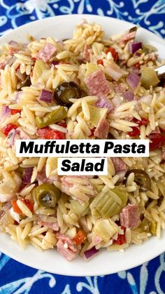 a white plate topped with pasta salad and meat on top of a blue table cloth