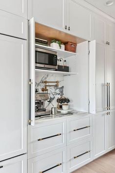 a kitchen with white cabinets and marble counter tops, gold pulls on the door handles