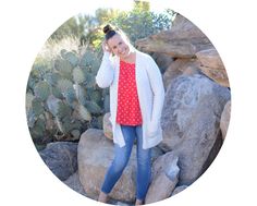 a woman standing in front of rocks talking on her cell phone with cactus behind her