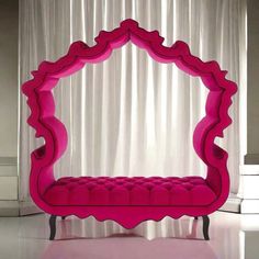 a pink couch sitting on top of a white floor next to a curtained window