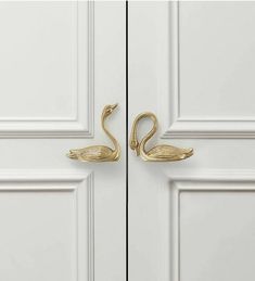 two brass swan hooks on the front door of a white painted room with paneled doors