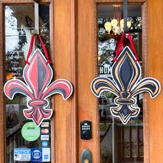 two decorative fleur de lis signs hang on the front door of a building