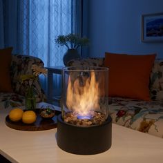 a living room filled with furniture and a fire in the middle of the floor next to a window