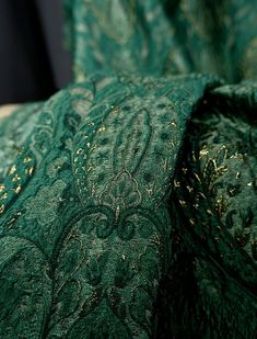 closeup of green and gold brocades on a bed