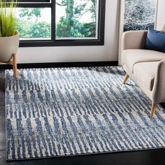 a living room area with a couch, chair and rug in front of a window