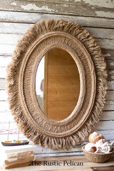 a round mirror sitting on top of a wooden table next to a basket filled with shells