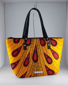 "\"Bag description:  This lovely bag is a perfect size for any occasion, with ample room for all your essentials when shopping, going to the office or on an evening out. The peacock design in yellow and wine also look great against a little black dress brightening the autumn day. This tote bag is a combination of Ankara African fabric and faux leather, fully lined waterproof canvas fabrics. The handles are long enough to fit comfortably on the shoulder or held by hand. Internally, this bag is fully lined with waterproof canvas and zippered pocket which fits your phone or other valuables. This bag is closed with a durable zip. Bag Style: Tote Fabric: African Wax Print Fabric - Ankara yellow and wine print fabric. 100% Cotton Lining: Waterproof canvas Hardware: Chrome  Handles: 24 inches in Trendy Yellow Bag With Removable Pouch, Trendy Yellow Double Handle Bag, Yellow Handheld Bag For Shopping, Yellow Handheld Shopping Bag, Trendy Yellow Shoulder Bag, Yellow Handheld Bag, Trendy Yellow Box Bag With Removable Pouch, Yellow Satchel Bag For On-the-go, Yellow Satchel With Top Carry Handle For On-the-go