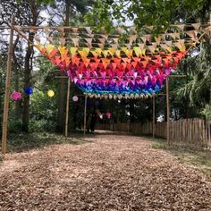 an outdoor area with many colorful decorations hanging from the ceiling and trees in the background