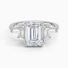 an emerald - cut diamond ring with baguets on the shoulders and side stones