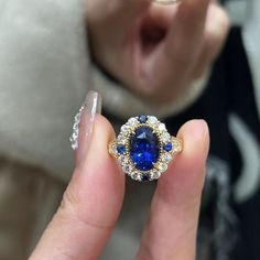 a close up of a person's hand holding a ring with a blue stone