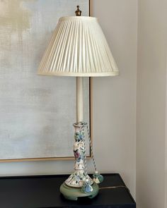 a lamp sitting on top of a table next to a painting