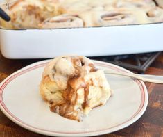 a cinnamon roll sitting on top of a white plate next to a casserole dish