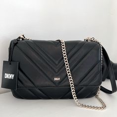 Covered In Eye-Catching Quilting, Dkny's Polished Veronica Bag Has A Timeless Appeal That's Modernized By A Minimalist Silhouette. Quilted Leather Crossbody Bag From Dkny Featuring Black, Lambskin, Quilted Finish, Silver-Tone Logo Lettering, Foldover Top With Magnetic Fastening, Leather And Chain-Link Shoulder Strap, Logo-Print Lining, Main Compartment, Internal Logo Patch And Internal Zip-Fastening Pocket. Dimensions: 9 3/4" Length X 6 3/4" Height X 3.5 Depth Drop: 12.5" (Handles) & 23" (Strap) Chic Bags With Silver-tone Logo Plaque For Everyday Use, Shoulder Bag With Silver-tone Logo Plaque For Everyday Use, Chic Rectangular Bags With Silver-tone Logo Plaque, Chic Evening Bag With Silver-tone Logo Plaque, Black Bag With Silver-tone Logo For Everyday Use, Modern Shoulder Bag With Silver-tone Logo Plaque, Chic Black Bag With Silver-tone Logo Plaque, Dkny Luggage, Silver-tone Logo Plaque Shoulder Bag