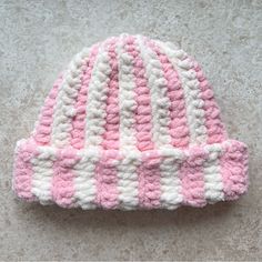 a pink and white knitted hat laying on the ground