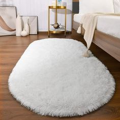 a large white rug on the floor in a room with wood floors and bedding