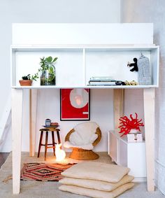 a white shelf with books and pictures on it next to a chair, table and stool