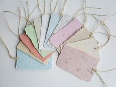 five different colored tags hanging from twine on white surface with string attached to them