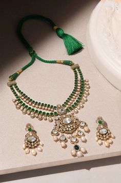 Unveil timeless elegance with this Layered Green Pendant Necklace Set, crafted with precision and style. The set is made from durable brass with a lustrous yellow gold finish, featuring a cascade of layers that exude sophistication. At its heart is a striking green emerald pendant, framed by sparkling Polki stones for an added touch of glamour. Delicate pearls are interspersed throughout, lending a classic, refined feel to the design. The vibrant green hues are balanced by the warm gold and the Opulent Gold Necklace For Gift, Opulent Hand Set Necklace For Gift, Opulent Gold Jewelry Gift, Gold Bridal Necklace With Detachable Pendant As Gift, Elegant Gold Bridal Necklace With Detachable Pendant, Exquisite Gold Kundan Necklace, Exquisite Gold Necklaces For Celebration, Luxury Yellow Gold Necklaces For Festive Occasions, Gold-plated Necklace With Detachable Pendant For Wedding