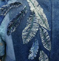 the back of someone's jean jacket that has been embroidered with leaves on it