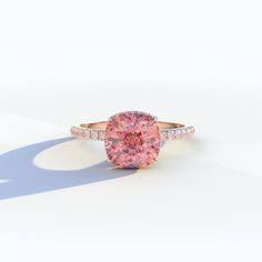 a pink diamond ring with diamonds on the band and an oval shaped stone in the center