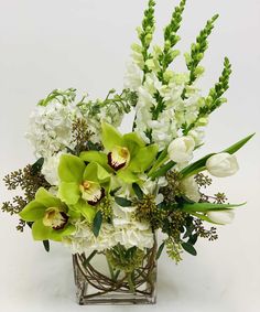 Wonderful in White | Whites and Greens in this traditional masterpiece.  Snaps, tulips, stock, hydrangea, orchids and seeded Euc and a clear rectangle vase .  Fragrant and fresh - classic look. #ToblersFlowers White And Green Flower Arrangements, Luxury Flower Arrangement, Rectangle Vase, Floral Designs Arrangements, Tropical Flower Arrangements, Green Centerpieces, Small Flower Arrangements, White Flower Arrangements, Large Flower Arrangements