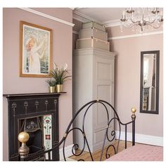 a bedroom with pink walls and a black iron bed frame in the corner, next to a fireplace