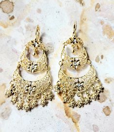 Beautiful traditional Mexican dangling earrings with 14k gold plated and small shiny imitation stones. These beautiful dangling earrings are the ideal gift for any occasion, they can be combined with any outfit both day and night, you will surely look beautiful because they will enhance your beauty making you look distinguished. Features/ Product info -The Main Material: Brass (14k Gold Plated) -Color: Gold - Earrings: 2.83 in (7.2 cm.) (H) 1.33 (W) (3.4 cm) -Earrings weight: (7 grams) Jewelry Love: Your Essential Guide to Caring for Your Treasures -Avoid tangles and snags by handling with care. -Store in a dry, cool place, away from sunlight to prevent damage. Take care to keep it flat to avoid any deformation.  -Put on after applying makeup and perfume. Also, make sure that any creams, b Frida Kahlo Earrings, Makeup And Perfume, 14k Gold Plated Jewelry, Mexican Earrings, Applying Makeup, Enhance Your Beauty, Traditional Earrings, Traditional Mexican, Dangling Earrings