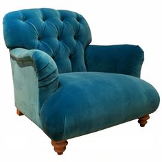 a blue velvet chair with wooden legs