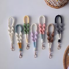 six different colored lanyards are lined up on a white surface with a basket in the background