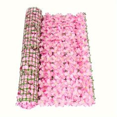 pink flowers are laid out next to a roll of wire mesh on a white background