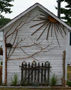 an old white house with sunbursts on the side and fence in front