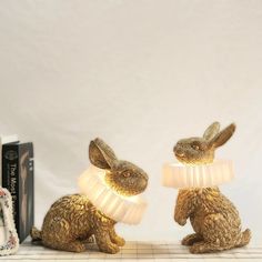 two golden rabbit lamps sitting next to each other