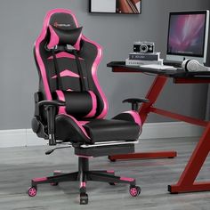 a pink and black office chair sitting in front of a computer desk with a monitor