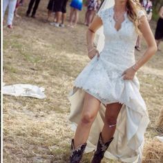 a woman in a white dress and cowboy boots is posing for the camera while people look on