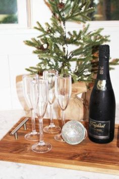 there is a bottle of wine and glasses on the tray next to it, with a christmas tree in the background