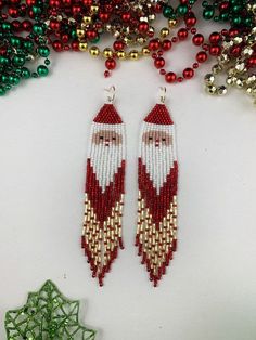 beaded santa claus earrings with red, white and green beads next to a christmas tree ornament