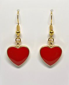 a pair of red heart shaped earrings hanging from gold earwires on a white background