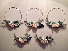 three hoop wreaths with flowers and greenery hanging on the wall