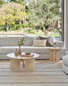 a living room filled with furniture and a large window overlooking the trees outside on a sunny day