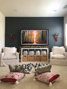 the living room is decorated for christmas with white furniture and red pillows on the floor