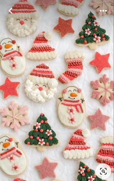 christmas cookies decorated with icing and decorations on a white tablecloth covered in snowflakes