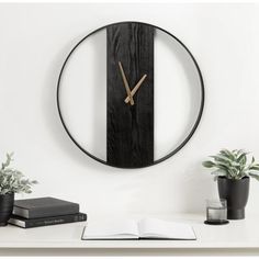 a clock that is on the wall next to a potted plant and some books