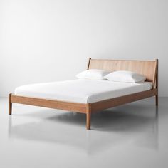 a bed with white pillows and wooden frame