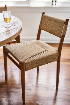 a wooden chair sitting next to a table with a glass on it's back