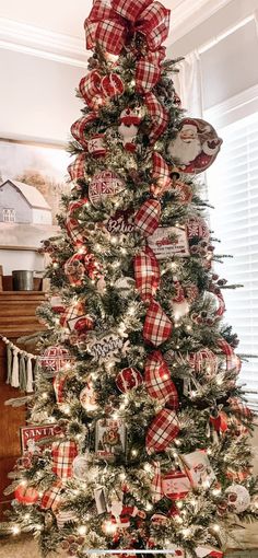 a christmas tree decorated with red and white plaid ribbon, ornaments, and bow on it