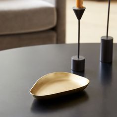 a black table with a gold plate on it and two candles in the middle next to it