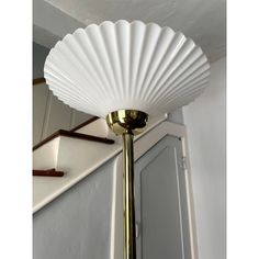 a white lamp sitting on top of a wooden table next to a wall mounted mirror